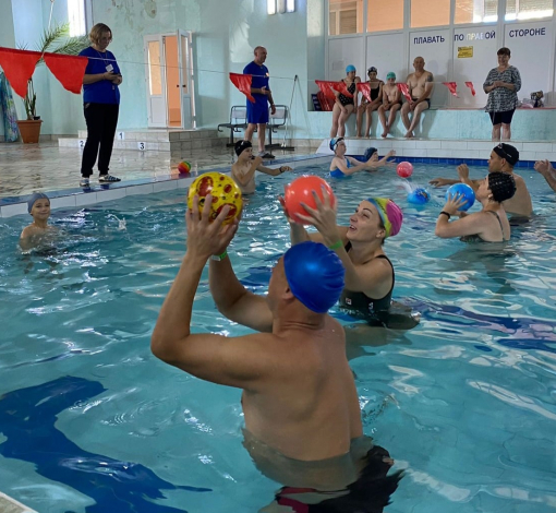 Семья Малютиных (ближний фон) стремится к победе в конкурсе - водный волейбол.