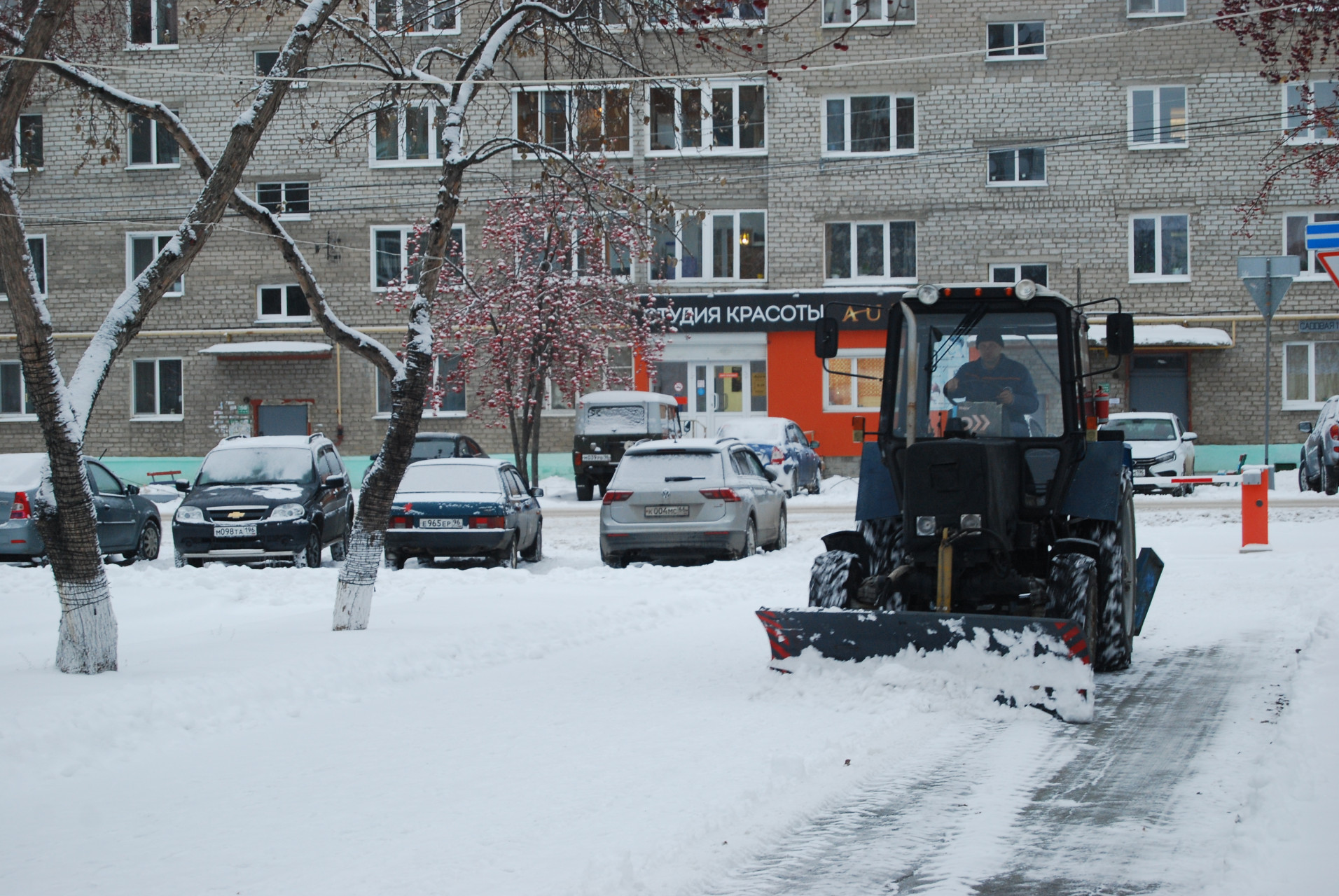 Синий трактор “Вентпома” при снегопаде резво бегает от проходной завода к улице Садовая и обратно. Снег здесь убирают “под гребенку”.