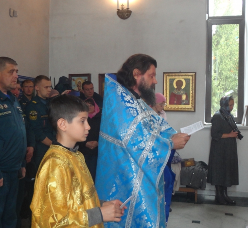 Отец Андрей читает молебен. Пожарные тихо крестятся.