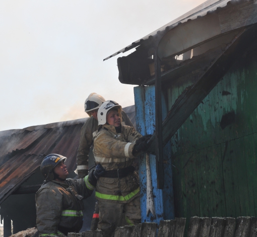 Пожарные отрывают доски от франтона дома, чтобы подобраться к ушедшему под крышу огню