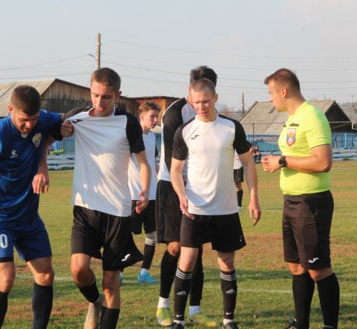 Михаил Савченко помогает травмированному игроку "Русала" (в белом) покинуть поле. Игроки гостей в это время спорят с арбитром.