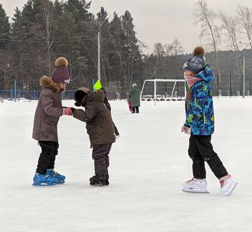 Ребята постарше учат малышей стоять на коньках.